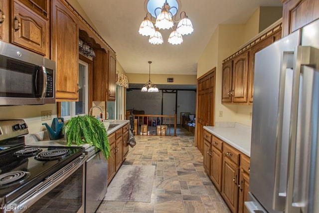 kitchen featuring hanging light fixtures, sink, stainless steel appliances, and an inviting chandelier