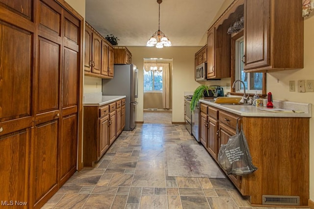 kitchen with pendant lighting, sink, stainless steel appliances, and a chandelier