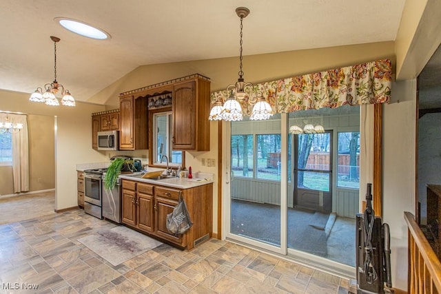 kitchen with appliances with stainless steel finishes, vaulted ceiling, a wealth of natural light, and pendant lighting