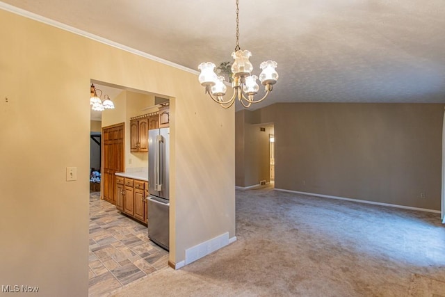 kitchen featuring crown molding, decorative light fixtures, vaulted ceiling, stainless steel fridge, and a notable chandelier