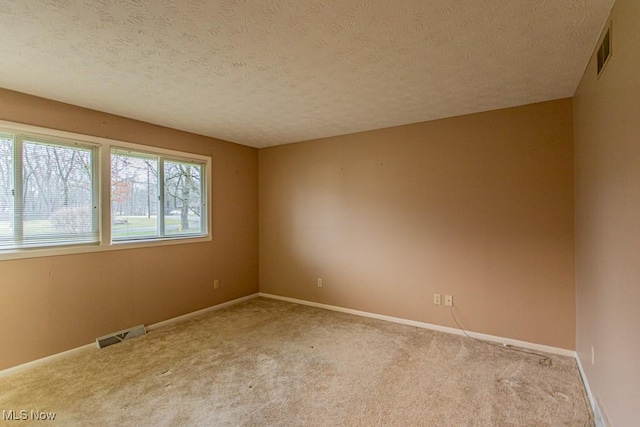 carpeted spare room with a textured ceiling