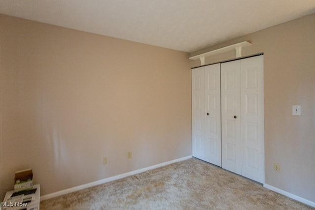 unfurnished bedroom featuring light carpet and a closet