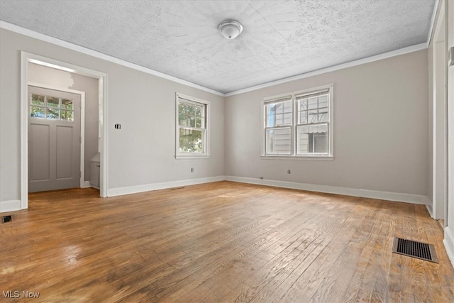 empty room with a textured ceiling, light hardwood / wood-style flooring, and ornamental molding