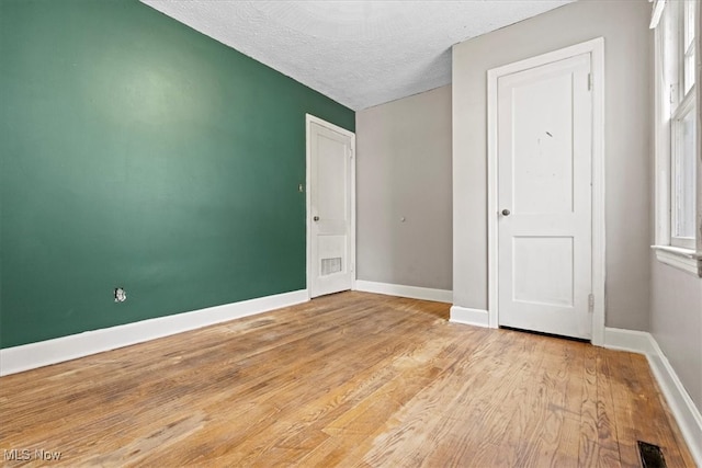 unfurnished bedroom featuring a textured ceiling, light hardwood / wood-style floors, and multiple windows