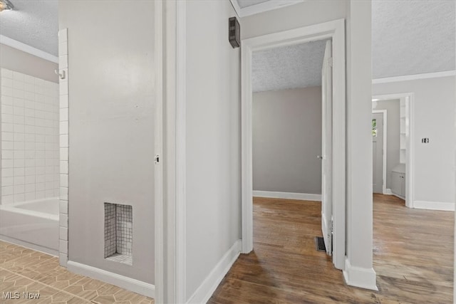 hallway with ornamental molding, a textured ceiling, and hardwood / wood-style floors