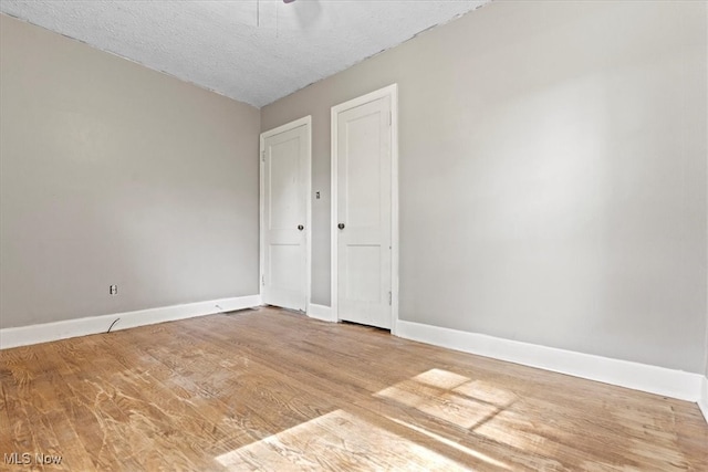 unfurnished room with a textured ceiling and hardwood / wood-style floors