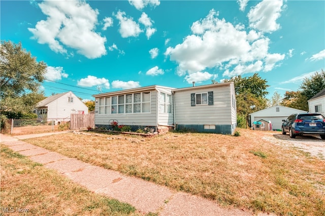 manufactured / mobile home with a garage, a front lawn, and an outbuilding