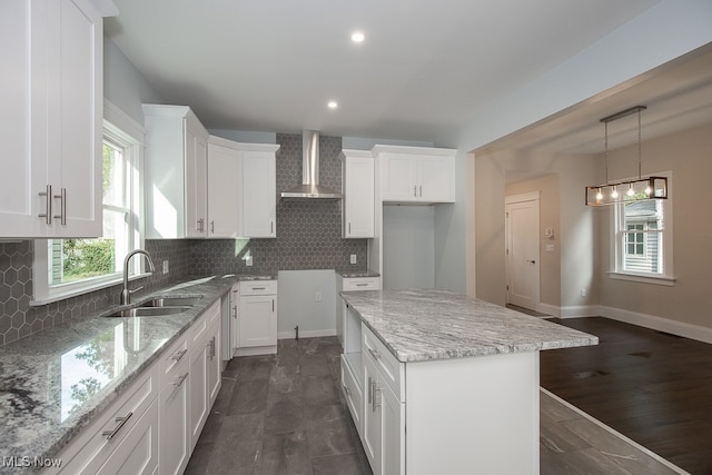 kitchen featuring white cabinets, a kitchen island, dark wood-type flooring, wall chimney range hood, and decorative backsplash