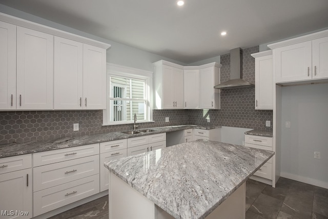 kitchen featuring a kitchen island, wall chimney range hood, and white cabinets