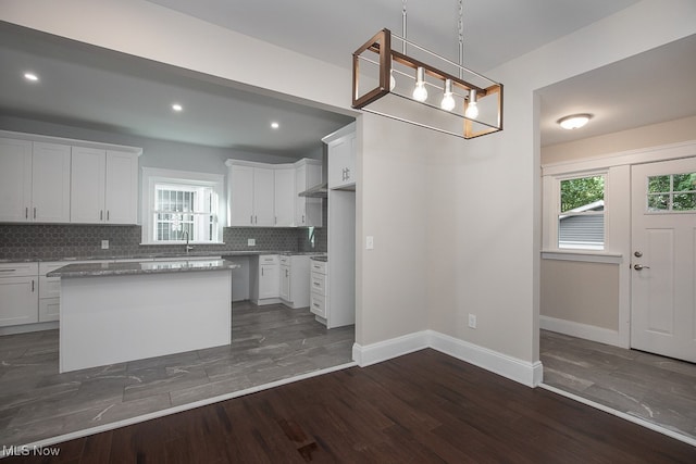 kitchen with backsplash, a kitchen island, dark hardwood / wood-style flooring, and white cabinets