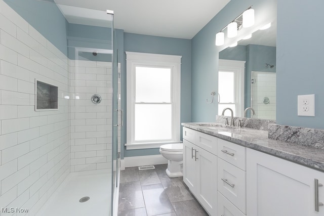 bathroom featuring a healthy amount of sunlight, vanity, toilet, and an enclosed shower