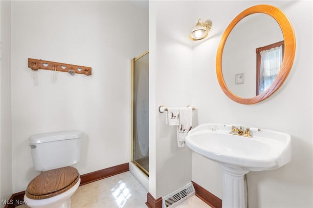 bathroom featuring a shower with door, toilet, and tile patterned floors