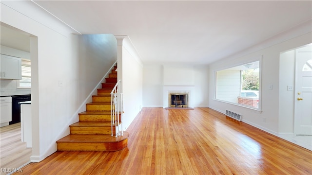 unfurnished living room with a fireplace, light hardwood / wood-style flooring, and plenty of natural light