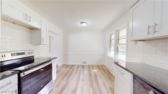 kitchen featuring dark stone countertops, white cabinets, stainless steel appliances, and backsplash