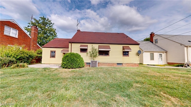 back of property featuring a lawn and cooling unit