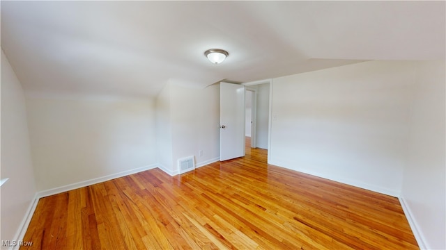 spare room featuring vaulted ceiling and light hardwood / wood-style flooring