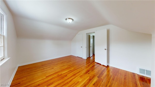 additional living space featuring light wood-type flooring and vaulted ceiling