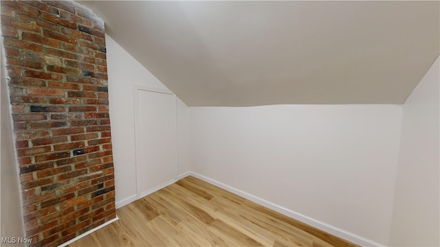 additional living space with light wood-type flooring and lofted ceiling