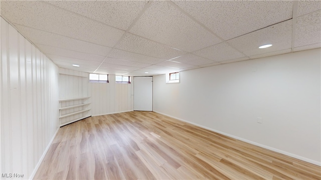 basement featuring a drop ceiling and light hardwood / wood-style flooring