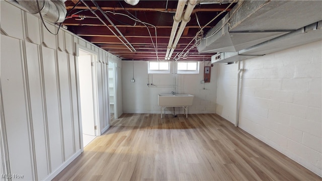 basement with light hardwood / wood-style flooring and sink