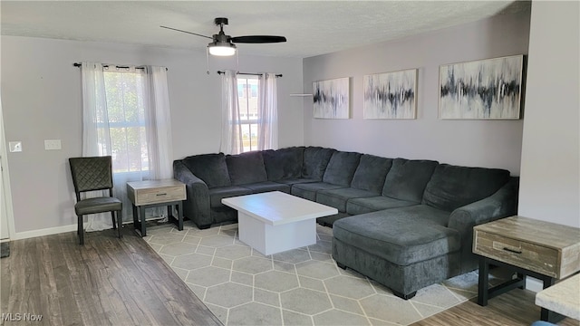 living room with ceiling fan, a textured ceiling, and light wood-type flooring