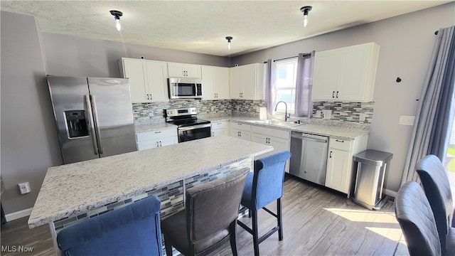 kitchen with pendant lighting, a center island, sink, appliances with stainless steel finishes, and hardwood / wood-style floors