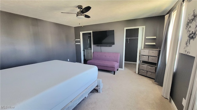 bedroom with ceiling fan, light colored carpet, a closet, and a spacious closet