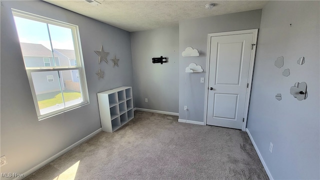 unfurnished room with light carpet, a textured ceiling, and plenty of natural light