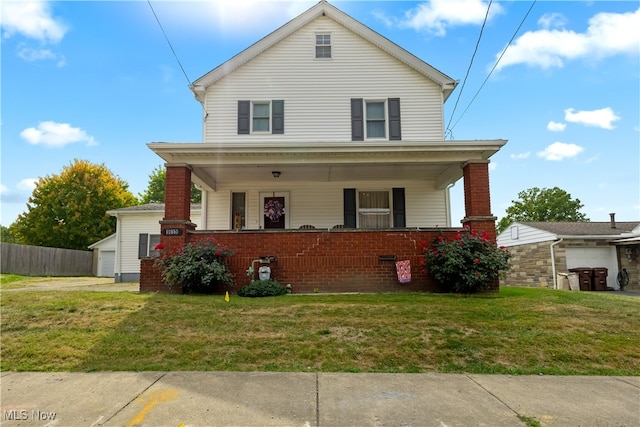 american foursquare style home with a front lawn, a porch, an outdoor structure, a garage, and brick siding