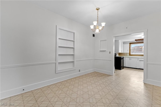 unfurnished room featuring light floors, built in shelves, baseboards, and an inviting chandelier