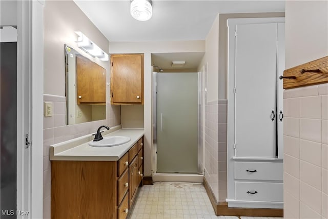 bathroom with a stall shower, vanity, tile walls, and tile patterned floors