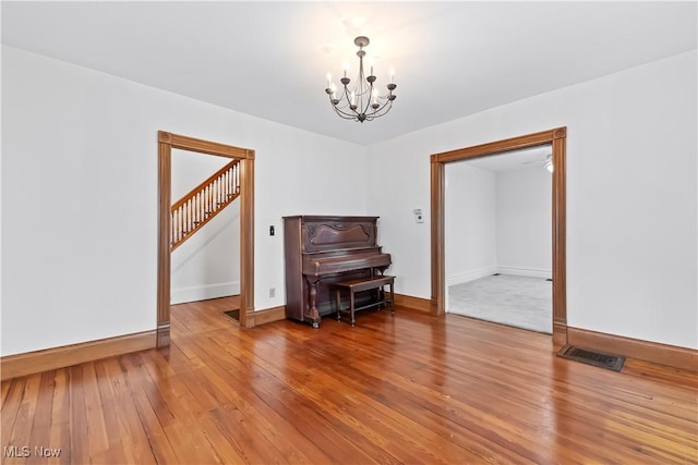 interior space with baseboards, wood-type flooring, visible vents, and a notable chandelier