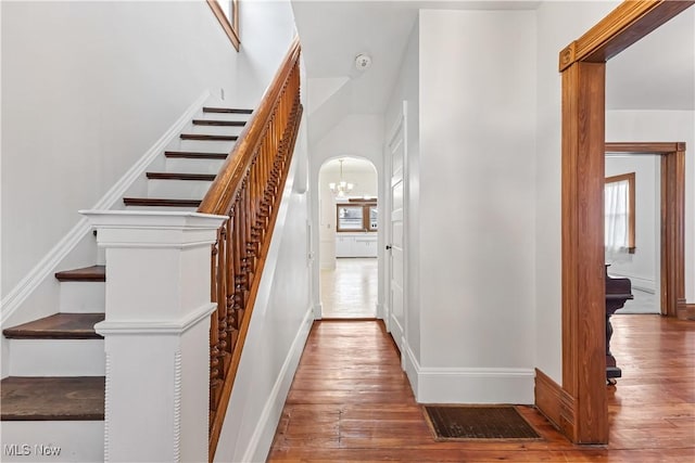 stairway with hardwood / wood-style flooring, baseboards, and arched walkways