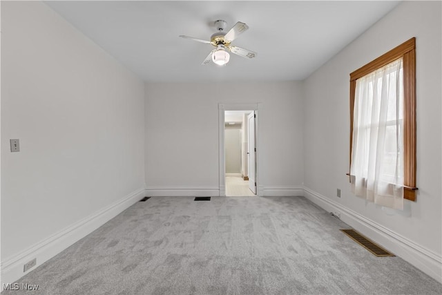 spare room featuring a ceiling fan, visible vents, light carpet, and baseboards