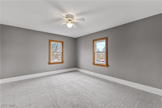 carpeted spare room with a healthy amount of sunlight, ceiling fan, and baseboards