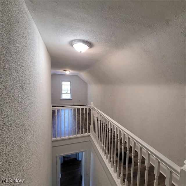 staircase with lofted ceiling and a textured ceiling