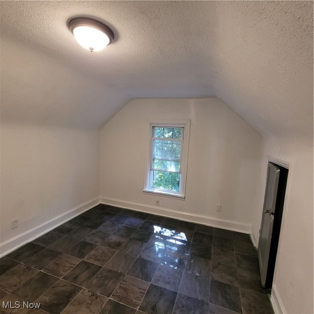 bonus room featuring lofted ceiling and a textured ceiling