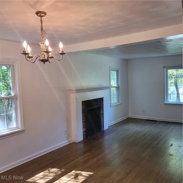 unfurnished living room with a fireplace, dark hardwood / wood-style floors, and a chandelier