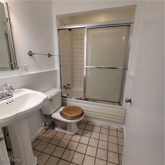 bathroom with tile patterned floors, enclosed tub / shower combo, and toilet