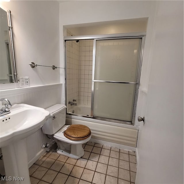 full bathroom featuring bath / shower combo with glass door, sink, toilet, and tile patterned floors