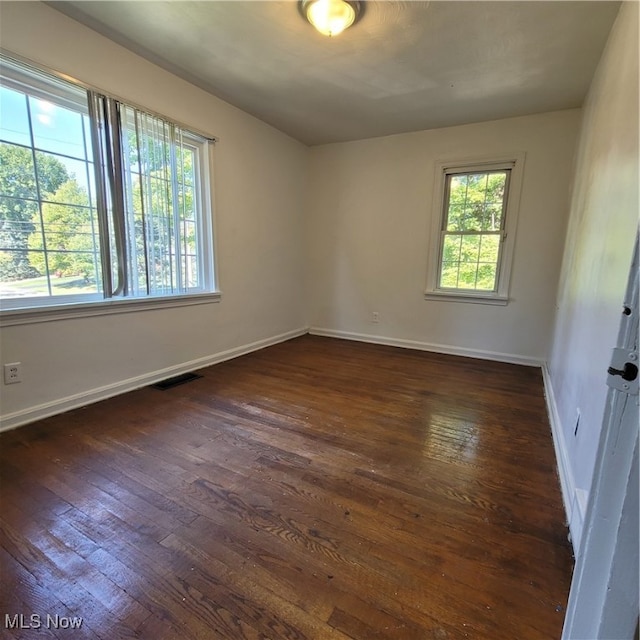 empty room with dark wood-type flooring and plenty of natural light