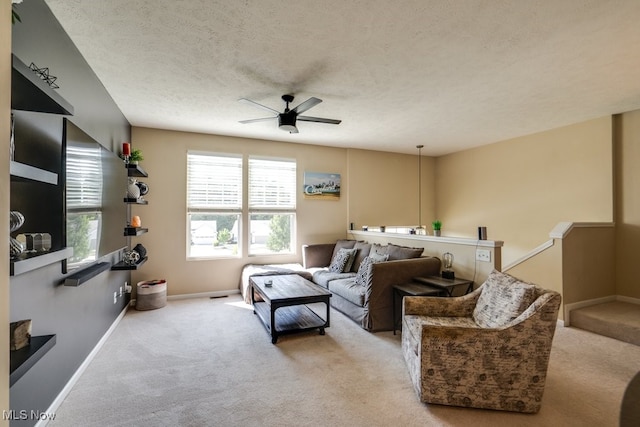 living room with ceiling fan, a textured ceiling, and light carpet