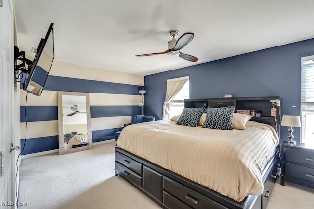 carpeted bedroom featuring multiple windows and ceiling fan