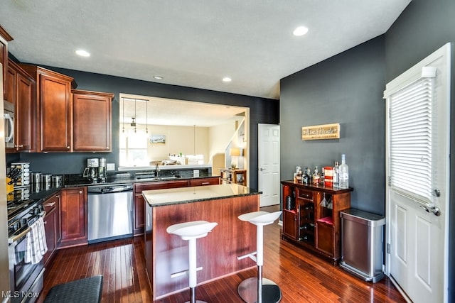 kitchen featuring appliances with stainless steel finishes, a kitchen island, sink, and dark wood-type flooring