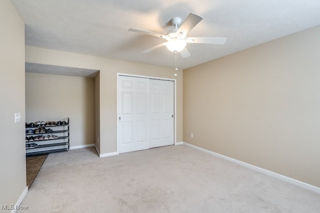 unfurnished bedroom featuring ceiling fan, a textured ceiling, a closet, and light carpet