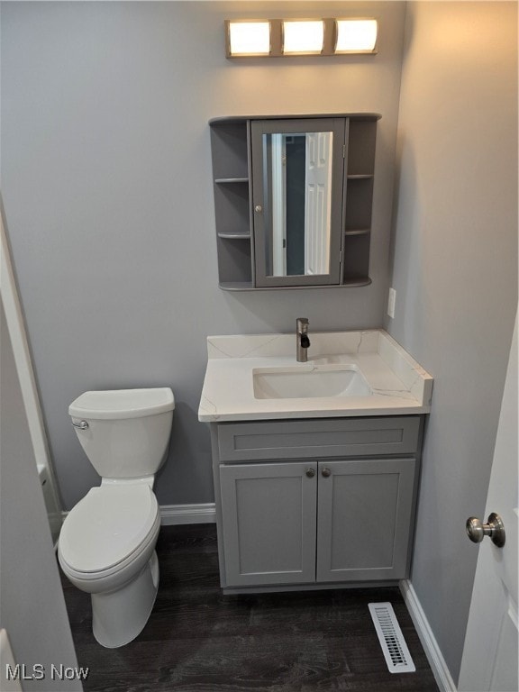 bathroom with wood-type flooring, vanity, and toilet