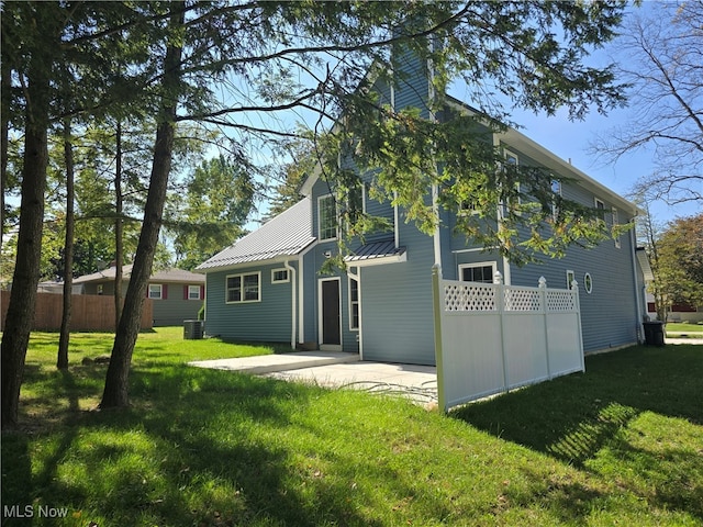 rear view of property with cooling unit, a yard, and a patio