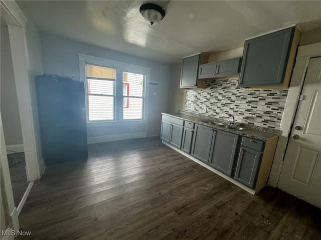 kitchen with gray cabinetry, backsplash, dark wood-type flooring, and sink