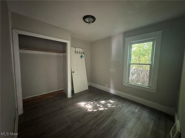 unfurnished bedroom with a closet and dark hardwood / wood-style floors