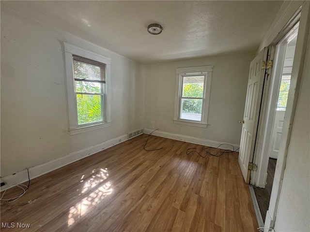 unfurnished room featuring hardwood / wood-style floors and a healthy amount of sunlight